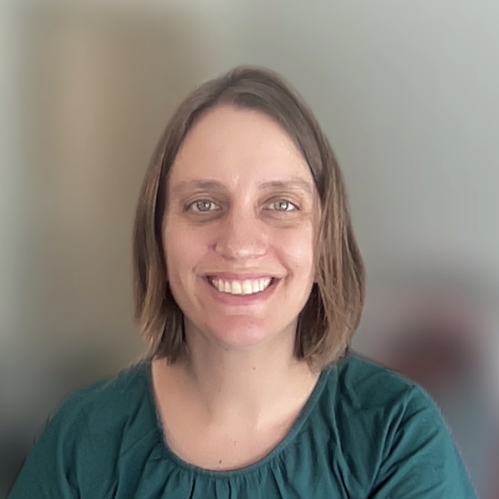 A women with short brown hair wearing a green shirt.